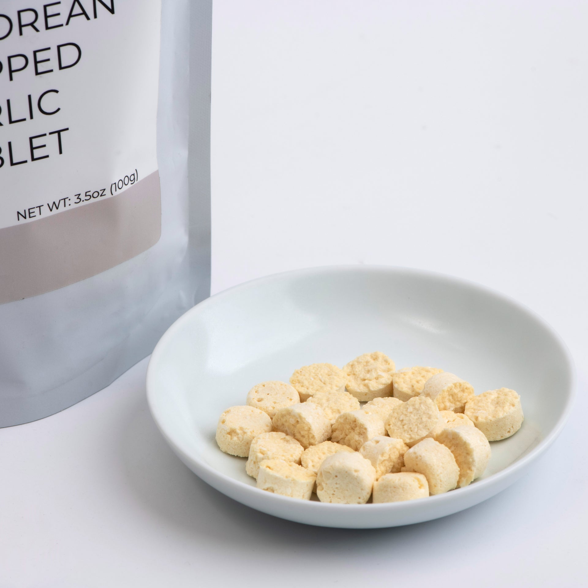 Freeze-dried chopped garlic pouch with bowl of garlic tablets