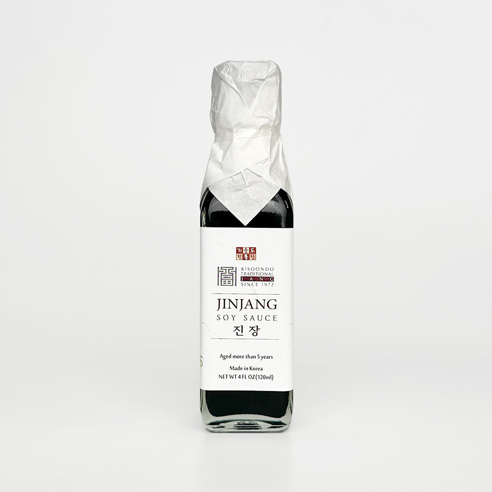 Aged soy sauce bottle with black liquid and white label, sealed in crinkled wrap