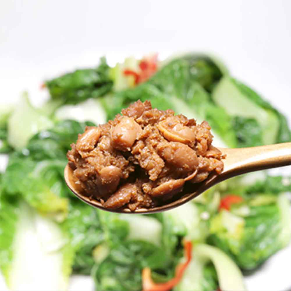 Spoonful of thick brown doenjang paste over greens