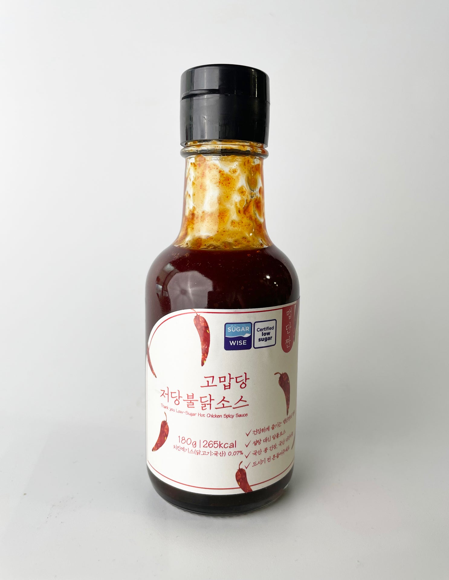 Low-sweet hot sauce bottle with red sauce, black cap, front label visible