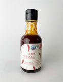 Low-sweet hot sauce bottle with red sauce, black cap, front label visible