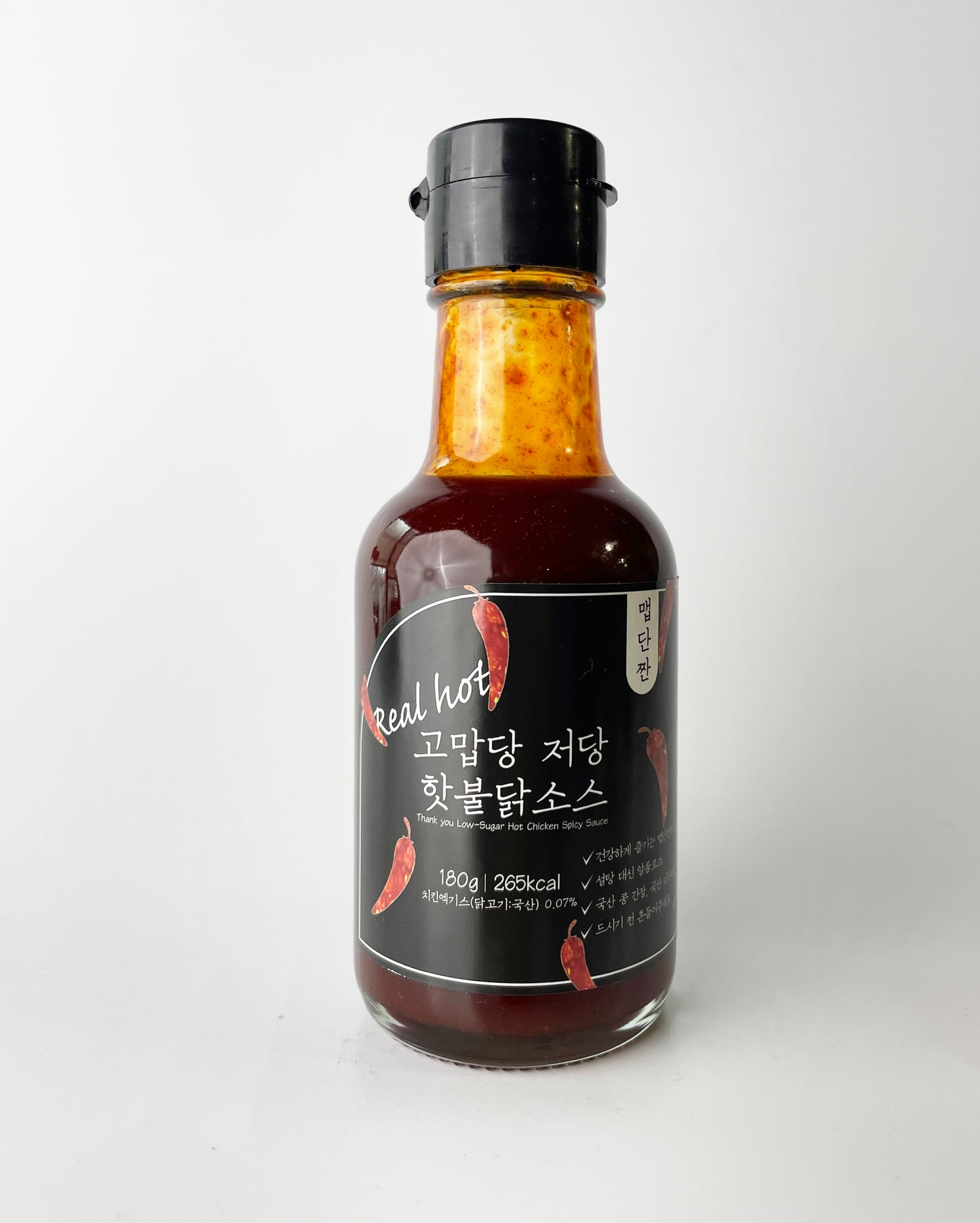 Low-sweet hot sauce bottle with red sauce, black cap, back label visible