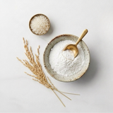 Bowl of white organic rice flour with wooden spoon and rice grains