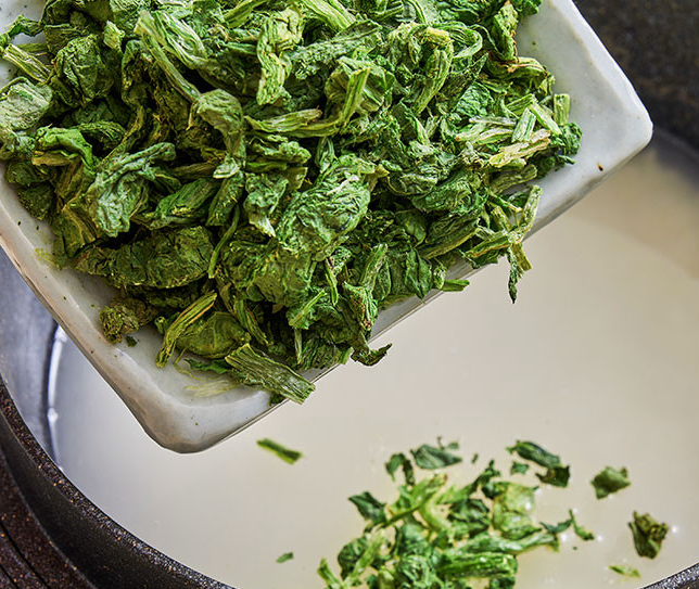Freeze-dried green leafy namul greens, scooped from a white dish