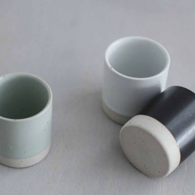 Sando shot cups, sage green and dark black outer cups with pale interiors.