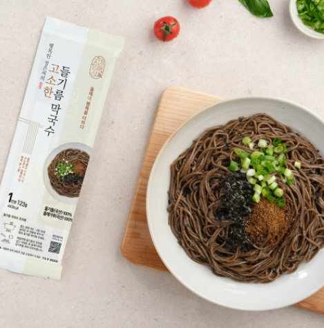 Buckwheat noodles in a white bowl with perilla oil topping and chopped scallions