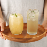 Organic yuzu juice in two glasses with mint garnish on a wooden tray