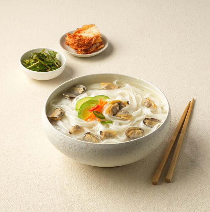 Bowl of thin rice noodles with clams and seaweed, chopsticks on the side