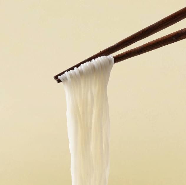 White thin rice noodles hanging from chopsticks, glossy strands