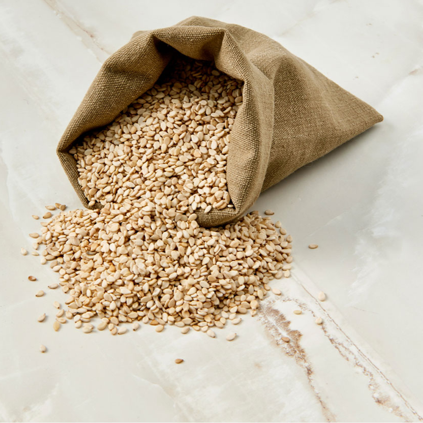 Sprouted sesame seeds in a burlap bag, seeds spilled across the surface