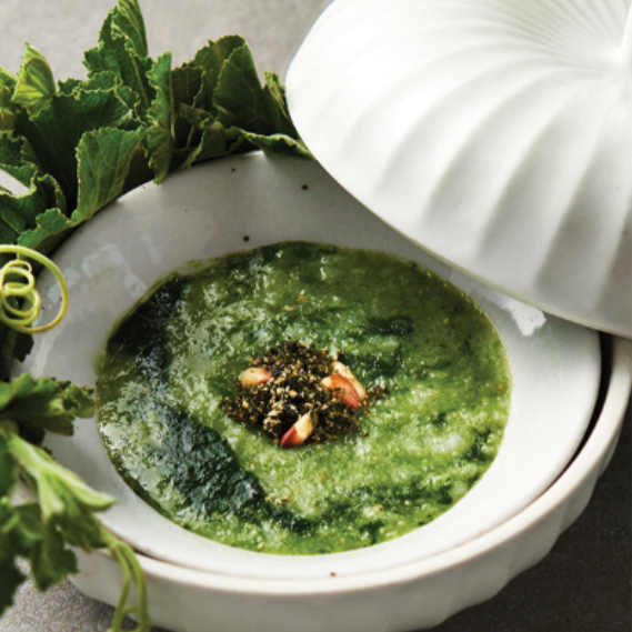 Green soup in white bowl with herb topping