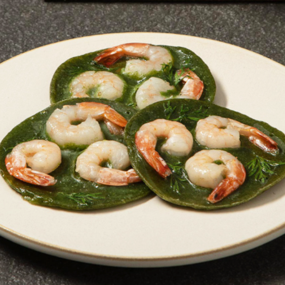Green crepes with shrimp on a white plate
