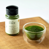 Powder jar with black lid and glass dish of fine green powder