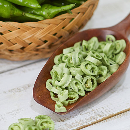 Sliced green chili peppers in a wooden spoon, ringed pieces