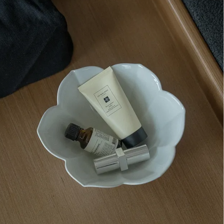 Flower tiny bowl set: white flower-shaped bowl holding skincare bottles and a cream tube.
