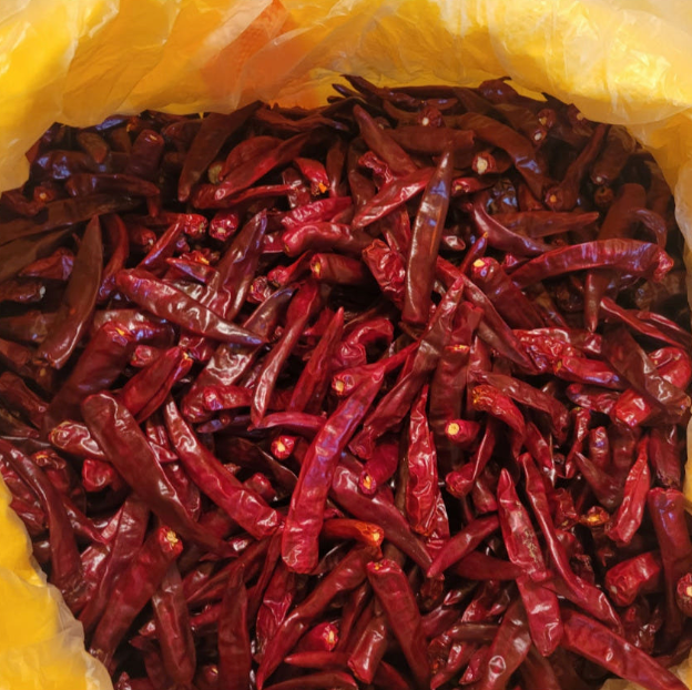 Coarse gochugaru dried red chili pods piled inside a yellow bag