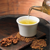 Cup of yellow buckwheat tea with pour stream from bottle