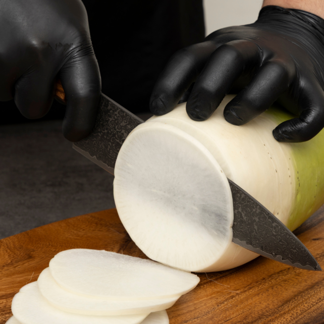Chef knife slicing an onion, dark Damascus blade and wooden handle