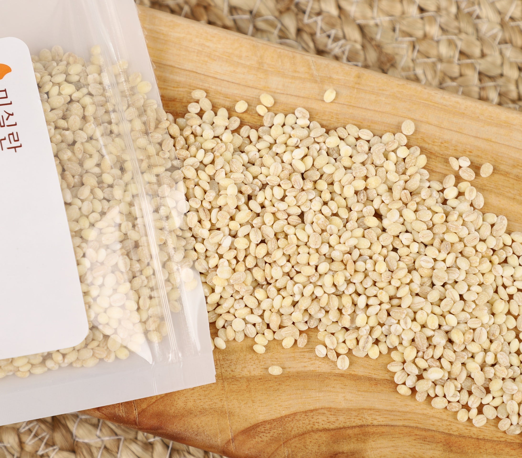 Organic glutinous barley grains, light beige, on wooden board with open pouch