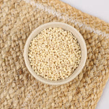 Glutinous barley grains in white bowl on woven mat, light beige