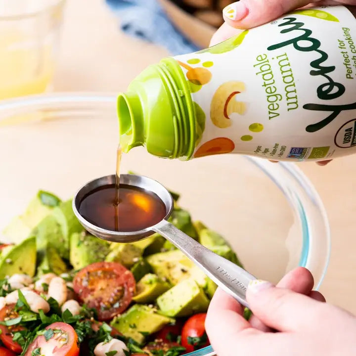Vegetable umami seasoning sauce bottle pouring into bowl with salad