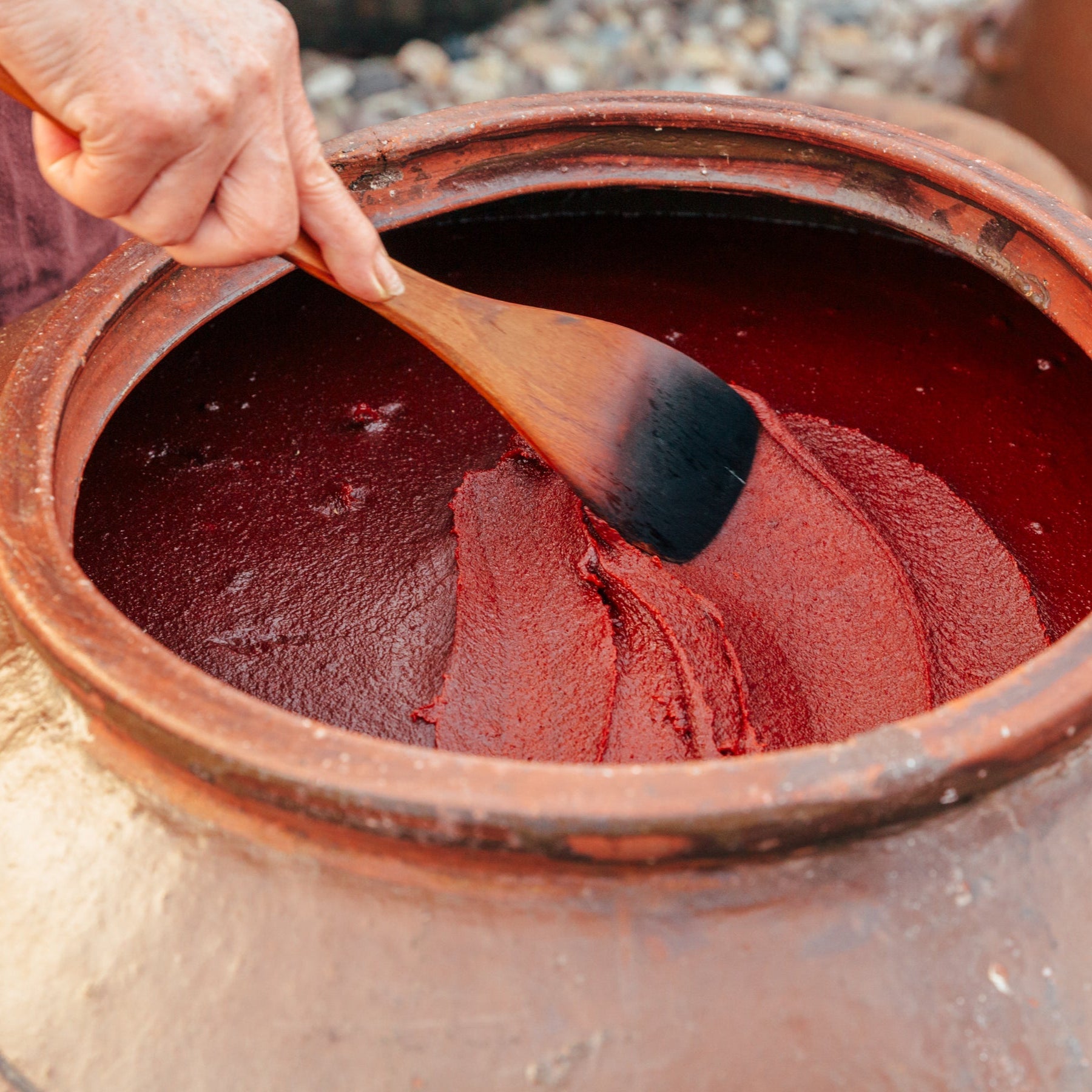 Ssamjang paste in a clay bowl, spread with a wooden spoon