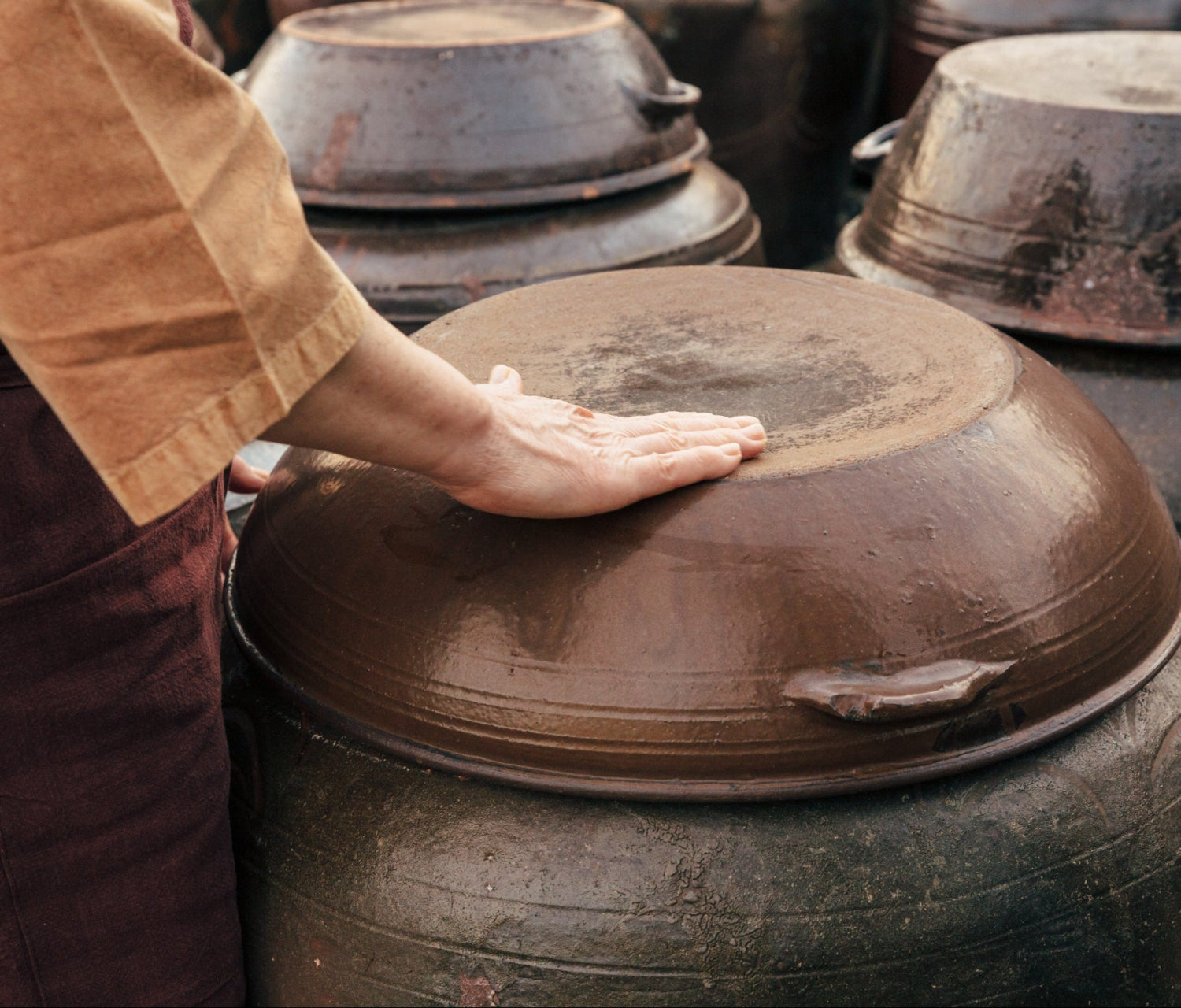 Metal cooking pot with lid as hands adjust it