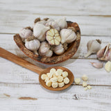 Garlic bulbs and chopped garlic tablets in wooden bowls and spoon