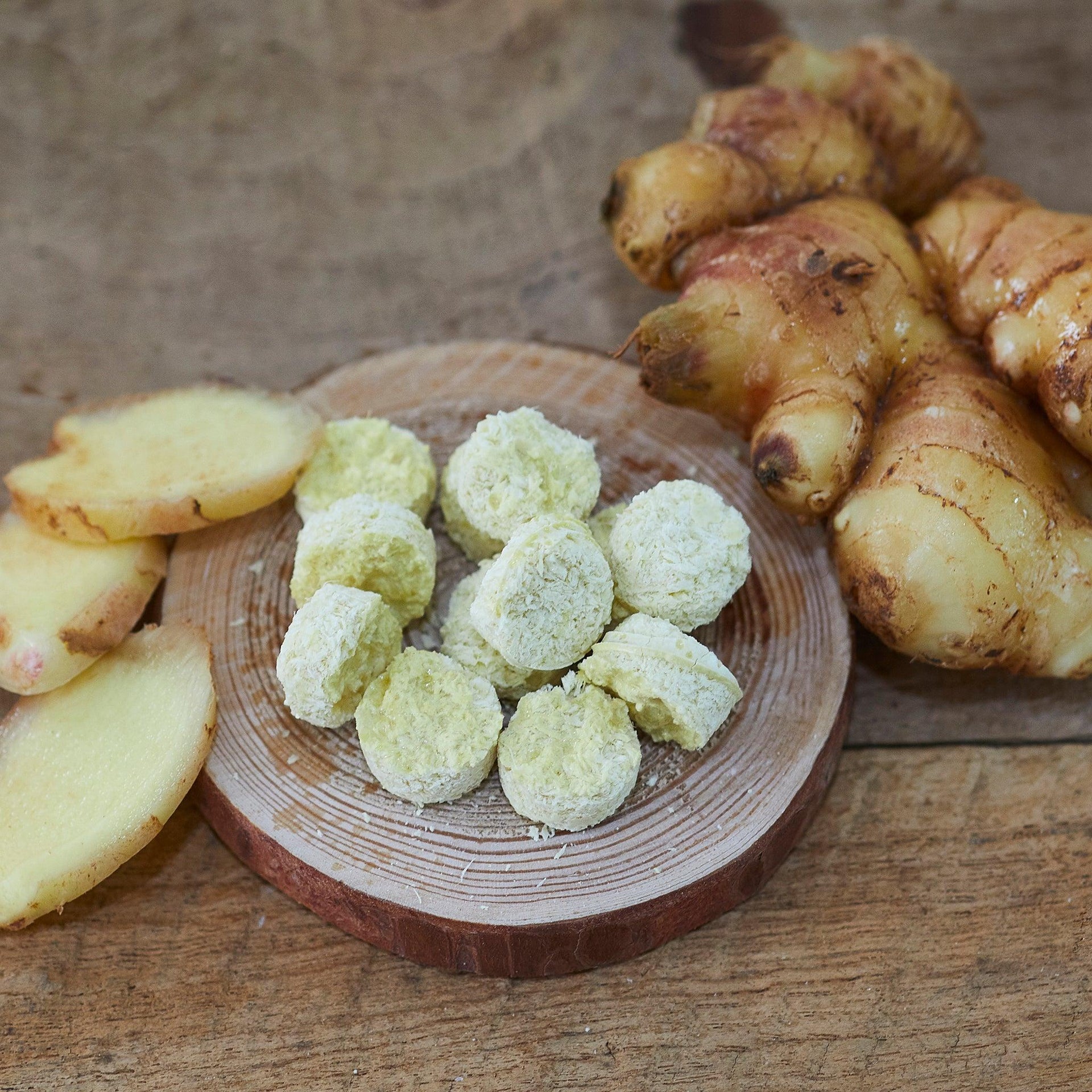 Freeze-dried minced ginger tablets with sliced ginger on a wooden dish
