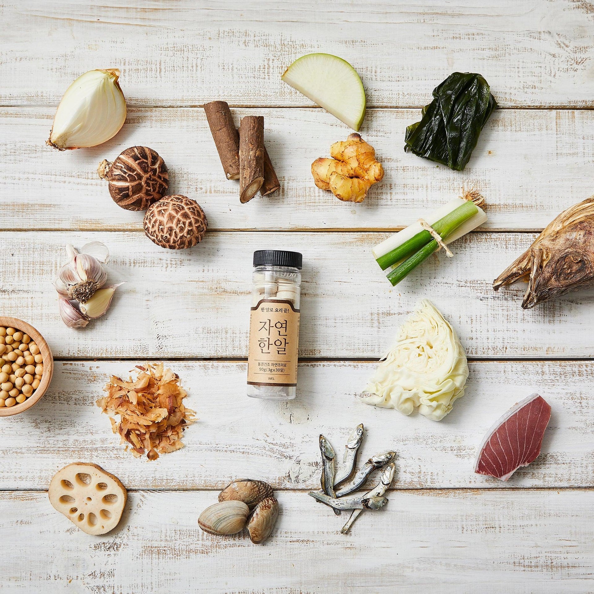 Natural seafood stock tablets bottle centered among assorted vegetables and seafood