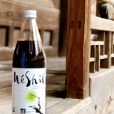 Organic Korean plum extract drink bottle on wooden display, MeShil label facing left