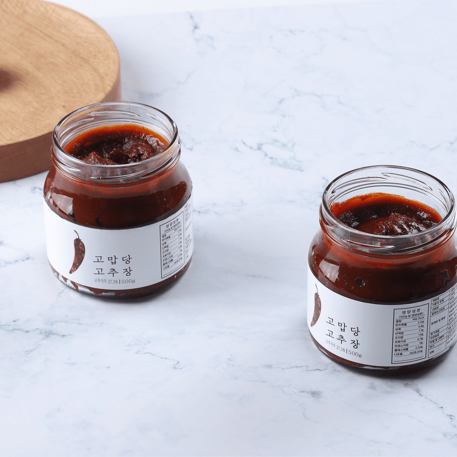Two THANKYOU Gochujang jars filled with dark red chili paste on a marble surface