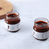 Two THANKYOU Gochujang jars filled with dark red chili paste on a marble surface