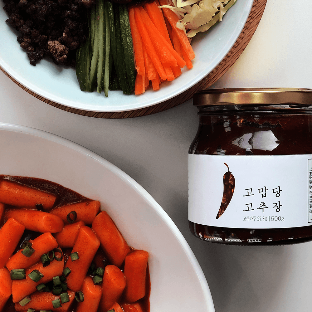 Gochujang jar with dark red chili paste, shown with sliced vegetables on plates