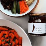 Gochujang jar with dark red chili paste, shown with sliced vegetables on plates